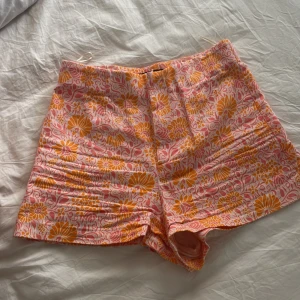 Kostym liknande shorts zara - Färgglada högmidjade shorts med blommigt mönster i orange, rosa och vitt. De har en fin passform och är gjorda i ett mjukt bomullstyg, perfekta för varma sommardagar. Knappt använda, från zara