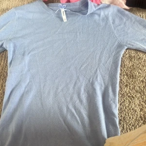 Ljusblå stickad tröja från Sinsay - Supersöt ljusblå stickad tröja från Sinsay i storlek XS. Tröjan har rund halsringning och långa ärmar, perfekt för lager-på-lager. Enkel och stilren design som är lätt att matcha med jeans eller kjol.