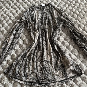 Ormmönstrad långärmad topp från Amisu - Säljer en långärmad topp från Amisu i storlek L med snyggt ormmönster i svart, grått och beige. Tunn och stretchig, perfekt att styla med jeans eller kjol för en cool look. Rund halsringning och figurnära passform.