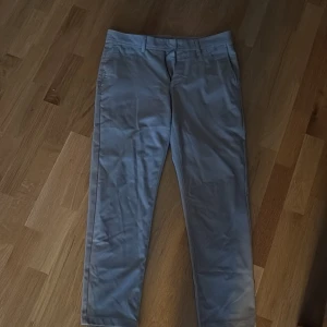 Beige chinos från Zara, storlek 40 - Snygga beige chinos från Zara i klassisk rak modell. Byxorna har bälteshällor, sidfickor och två bakfickor med knapp. Tillverkade i bomull för en skön och stilren känsla. Perfekta för en clean och avslappnad look.