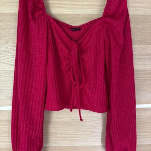 Ribbad röd/rosa blus  - Ribbad röd croppad topp från Gina Tricot❣️Toppen har långa puffiga ärmar, v-ringning och knyt framtill. Säljer då jag tröttnat på den!
