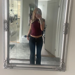 Lågmidjade jeans  - Säljer ett par svarta bootcut jeans från Gina young med låg midja. Jeansen har snygga fickdetaljer med knappar bak. Materialet är stretchigt jeans och passformen är normal. De är uppsprättade när nere för att de skulle bli lite längre. Kontakta för bilder