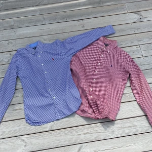 Två rutiga skjortor från Ralph Lauren - Säljer två klassiska rutiga skjortor från Ralph Lauren. En blåvit i slim fit (SP) och en rödvit i custom fit (M). Båda har knappar framtill, lång ärm och broderad logga på bröstet. Tillverkade i 100% bomull för en skön känsla och snygg passform.