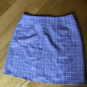 Lila rutig minikjol från Boohoo - Superfin lila kortkjol från Boohoo med vitt rutmönster. Kjolen har en klassisk rak passform och dragkedja bak. Perfekt att styla med en enkel topp eller oversized hoodie för en chill vibe.