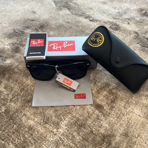 Svarta Ray-Ban Wayfarer solglasögon - Klassiska svarta Ray-Ban Wayfarer solglasögon med mörka glas. Snygg och tidlös design med Ray-Ban-logga på skalmen. Kommer med originalfodral, putsduk och box. Perfekta för att lyfta din stil i solen. Köptes på plick så kan ej garantera äkthet. Priset är inte hugget i sten vid snabb affär!