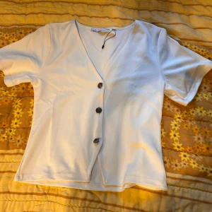 Vit blus  - Vit blus från 157 med v-ringning och tre snygga knappar framtill. Modellen är kortärmad och har en rak, lite loose passform. Helt ny aldrig använd!💕
