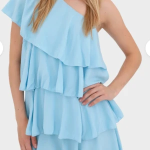 Ljusblå one shoulder volangklänning - Superfin ljusblå klänning med flera lager volanger och one shoulder-design. HELT NY med prislapp kvar. 