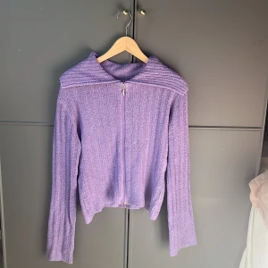 Lila stickad tröja med dragkedja - Säljer en snygg lila stickad tröja med dragkedja framtill. Tröjan har långa ärmar och en ribbad detalj vid axlarna. Perfekt för kyligare dagar och ger en mysig känsla. Passar bra till både jeans och kjol.💕