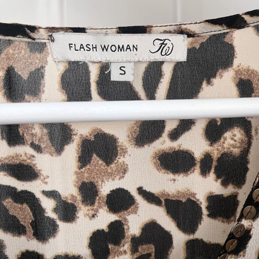 Snygg leopardmönstrad topp från Flash Woman med trekvartsärmar och snörning framtill. Perfekt för att ge en djärv touch till din outfit. 🐆. Puserot.