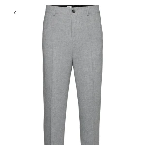 Grå kostymbyxor från Filippa K - Snygga grå kostymbyxor från Filippa K i en stilren design. Byxorna har en rak passform med knapp och dragkedja framtill. Perfekta för en elegant look.