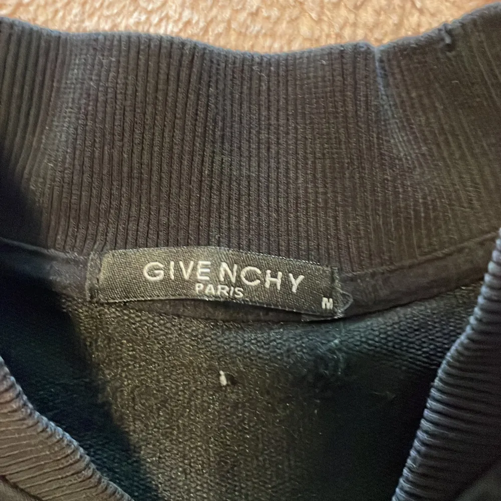Säljer en stilren svart bomberjacka från Givenchy med dragkedja framtill. Jackan har långa ärmar med Givenchy-logga längs sidorna i vitt och rött. Perfekt för en trendig look! Lite småfleckar. Kolla bild. . Takit.
