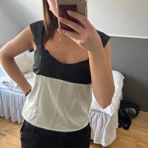 Svart och vit topp från Cider - Snygg svart och vit satintopp från Cider med breda axelband och en stilren design. Toppen har en enkel och elegant stil som passar till sommaren. Den är aldrig använd med prislappen kvar🙌🏻🙌🏻