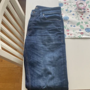 Blå jeans från Jack & Jones - Säljer ett par snygga blå jeans från Jack & Jones. De har en klassisk femficksdesign och en läderpatch med logotyp baktill. Perfekta för en stilren look.