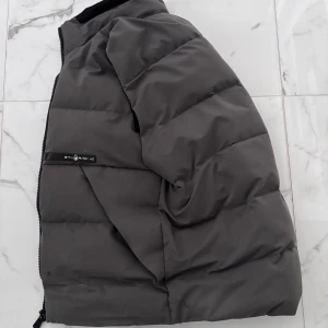 Grå dunväst från Sail Racing - Snygg grå dunväst från Sail Racing med dragkedja. Perfekt för kyligare dagar. Västen har en stilren design och är tillverkad med Sail Racing Technology för extra komfort.