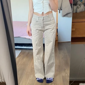 Beige jeans - Snygga beige byxor med hög midja och rak passform. Perfekta för en avslappnad stil. Byxorna har fickor och bälteshällor, vilket gör dem både praktiska och stilrena.