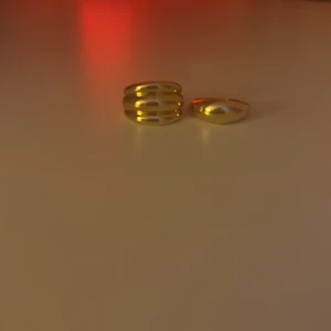Guldiga ringar i set - Två  guld ringar, en med en slät yta och den andra med en tredelad design. Perfekta för att bära tillsammans.