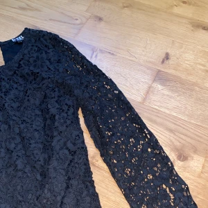 Vacker svart spetsblus från D-XEL - Säljer en elegant svart spetsblus från D-XEL. Blusen har långa ärmar och ett vackert blommigt spetsmönster. Den passar till allt möjligt. 