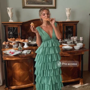 Grön volangklänning - Säljer denna  grön klänning med flera lager av volanger från Lovisa Wallin x NAKD. Slutsåld online och kostade 1800kr.  I nyskik då den var för stor för mig! Öppen för bud!