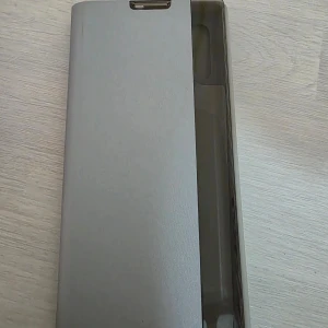 Grå mobilfodral, samsung galaxy note 10+ - Oavänd, syggt och praktiskt grått mobilfodral med flip-funktion. Fodralet har en slät yta och ett fönster för att se notifikationer utan att öppna det. Perfekt för att skydda din mobil samtidigt som du håller stilen. Passar till samsung galaxy note 10+