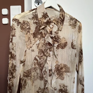 Beige & brun mönstrad mesh skjorta med vollang krage - Köpt på utvald vintage butik, aldrig använd, i fint skick. Super fräck. Säljer då jag känner att jag ej passar i beige.   Storlek ~ 38, skulle säga mer som 36.  Armlängd  ~ 38 cm Armlängd ~ 52 cm  Bredd Underarm ~ 43 cm Längd ~ 57 cm Bredd på tröjan, längst ner ~ 42 cm