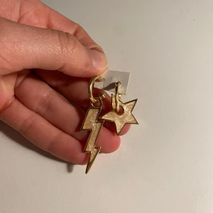 Guldörhängen med blixt och stjärna - Snygga guldörhängen med unika former: en blixt och en stjärna. Perfekta för att ge din stil en cool och edgy touch. Lätta att matcha med olika outfits.