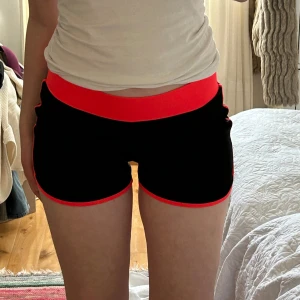 Svarta lågmidjade shorts - Snygga svarta lågmidjade shorts med korall elastisk midja och kant, från Guess. 