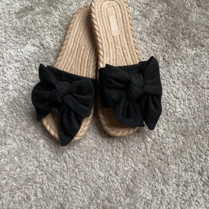 Super söta beiga sandaler med svarta rosetter, aldrig använda💗 - Snygga beige sandaler med en stor svart rosett på ovansidan. Perfekta för sommardagar med en bekväm sula och stilren design.