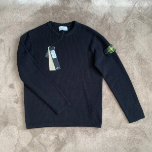 Svart Stone Island Tröja - Säljer en stilren svart ribbad Stone Island tröja. Tröjan är i storlek M men kan eventuellt också passa S då materialet är stretchigt. Den kommer med tags och det klassiska gröna Stone Island märket vid vänstra armen men även med en All Black Stone Island Badge (OBS bild 3) vid frågor eller funderingar skicka ett pm, Mvh