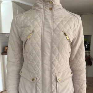 Beige jacka med dragkedjor - Snygg beige quiltad jacka med dragkedjor och knappar i guld. Perfekt för vår och höst🌼