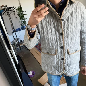 Grå quiltad jacka från Valstar - Säljer en stilren grå quiltad jacka från Valstar med bruna detaljer. Jackan har knappar framtill och två fickor med knappstängning. Perfekt för höst och vår. Nypris ca 9000kr