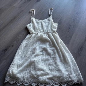 Vit spetsklänning med smala axelband - Säljer en söt vit klänning med smala axelband och vacker spetsdetalj. Klänningen har en elegant design med en fin kant längst ner. Perfekt för somriga dagar eller speciella tillfällen. 💫 funkar bättre som strandklänning