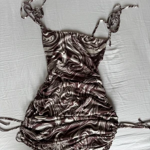 Mönstrad klänning från Nelly - Snygg klänning från NLY One. Klänningen har smala axelband som går att knyta efter sina egna preferenser och band i sidorna så kan även där kan spänna efter sina egna preferenser. Aldrig använd bara testad! Skriv gärna vid frågor eller bud ☺️