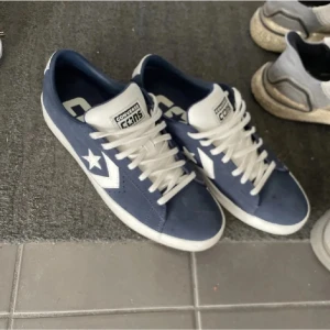 Blå sneakers från Converse - Snygga blå sneakers från Converse med vit sula och klassisk stjärndetalj på sidan. Skorna har snörning och är perfekta för en avslappnad stil. De är tillverkade i mocka och har en bekväm passform. Skorna är slutsålda, därav priset. Men prislappen kan sänkas vid smidig affär😁. 