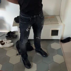 Svarta jeans från Dondup - Snygga svarta jeans från Dondup med slitna detaljer och en cool look. Tillverkade i Italien, dessa jeans har en klassisk femficksdesign och en knappgylf. Perfekta för en stilren och avslappnad stil.