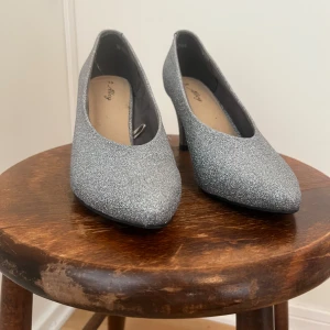 Glittriga pumps från Skopunkten storlek 39 - Snygga silverglittriga pumps med spetsig tå och klack från Skopunkten. Använda 1 gång! 