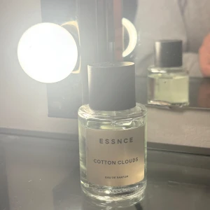Essnce Cotton Clouds Eau de Parfum - Fräsch och luftig doft från Essnce, Cotton Clouds Eau de Parfum. Flaskan är genomskinlig med en stilren etikett och svart lock. Perfekt för den som söker en lätt och upplyftande doftupplevelse. 