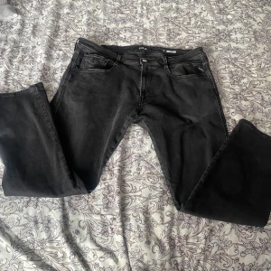 Svarta jeans från Replay - Snygga svarta jeans från Replay i storlek L. De har en klassisk design med dragkedja och knapp framtill. Perfekta för en stilren look.