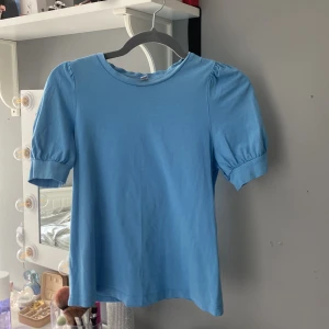 Blå topp från Vero Moda - Säljer en söt blå topp från Vero Moda med korta puffärmar. Toppen är i en mjuk bomullskvalitet och har en rund halsringning. Köpte för 199 kr och har bara använt väldigt få gånger  ❤️så passa på att köp !!💕