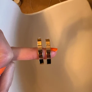 Guldiga örhängen i metall - Gina Tricot - Snygga och stilrena guldiga örhängen i metall. De har en bred design som ger en modern touch och passar perfekt för att lyfta vilken outfit som helst. Perfekta för både vardag och festliga tillfällen.