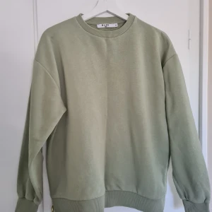 Grön oversized sweatshirt från NA-KD - Säljer en grön oversized sweatshirt från NA-KD. Tröjan har en rund halsringning och ribbade muddar vid ärmslut och nederkant.