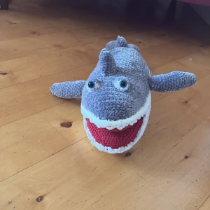 Haj leksak  - Charmig virkad haj i grått och vitt med en röd mun. Perfekt som en mysig kompis eller barnleksak.Den har stora ögon och en mjuk, kramvänlig kropp.