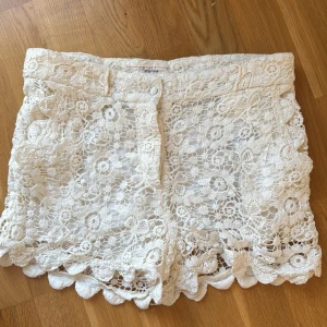 Vita spets shorts från Pepe Jeans - Säljer ett par vita spets shorts i vacker spetsdesign från Pepe Jeans. De har en fin blommig spetsdetalj och en bekväm passform. Perfekta för varma sommardagar! 🌸
