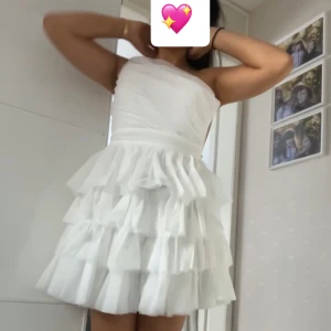 Vit oneshoulder klänning med volanger - Säljer en söt vit oneshoulder klänning med flera lager av volanger. Perfekt för sommarens fester. Klänningen har en kort längd och ger en luftig och elegant känsla.💖 Säljer pga att den är för liten, helt oanvänd!!🙌🏽