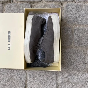  Axel Arigato skor - Gråa Axel arigato skor ,storlek 41 väldigt bra sick , säljer dom för att jag har växt ifrån dom , boxen finns men inget kvitto