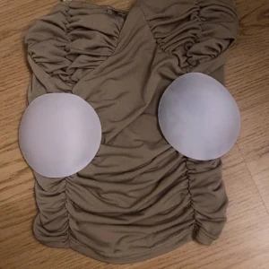 Beige korsettopp - Snygg beige korsettopp med rynkade detaljer och smala axelband. Perfekt för en stilren look. Använt max 3gånger passar bra för xs/s