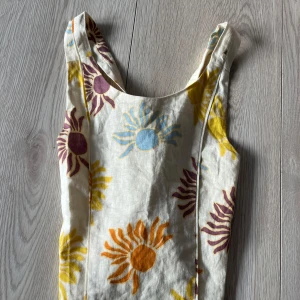 Linne  med solmönster och öppen rygg  - Charmig linne med ett färgglatt solmönster i gult, orange, blått och lila på en vit bakgrund. Perfekt för soliga dagar med sin lätta och luftiga design.🩷🩷