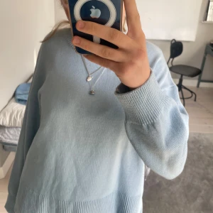 Ljusblå stickad tröja - Säljer en ljusblå stickad tröja med rund hals och långa ärmar. Tröjan har en ribbad kant vid ärmslut och nederkant, vilket ger en snygg detalj. Perfekt för en avslappnad stil.