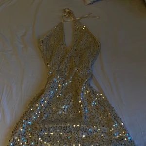 Glittrig klänning från NA-KD - Säljer en superglittrig klänning från NA-KD i en champagne färg . Klänningen har paljetter över hela och en v-ringad design med knytband i nacken. Perfekt för att glänsa på festen eller nyår! ✨