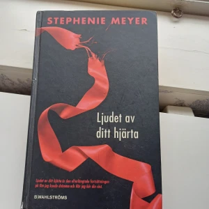 Ljudet av ditt hjärta - Boken 'Ljudet av ditt hjärta' av Stephenie Meyer är en spännande fortsättning i en populär serie. Den har ett dramatiskt omslag med en röd banderoll mot en svart bakgrund. Perfekt för dig som älskar romantik och övernaturliga berättelser.