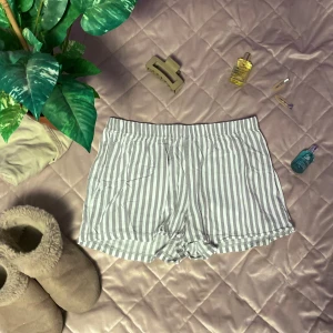 Randiga pajamas shorts från Female Passion - Säljer ett par bekväma randiga shorts från Female Passion. De är vita och grå med elastisk midja för extra komfort. Perfekta för en avslappnad dag hemma eller en promenad i solen.